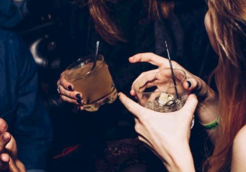 People are enjoying drinks and socializing in a lively setting, with smiles and dark attire visible.