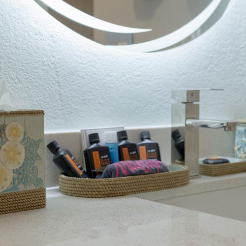 A bathroom counter with a tissue box, toiletries, and a soap dispenser on a white surface.
