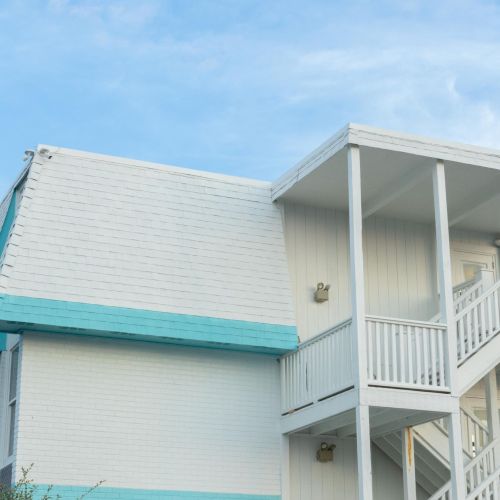 A white building with teal accents features multiple staircases and a blue sky as the backdrop.