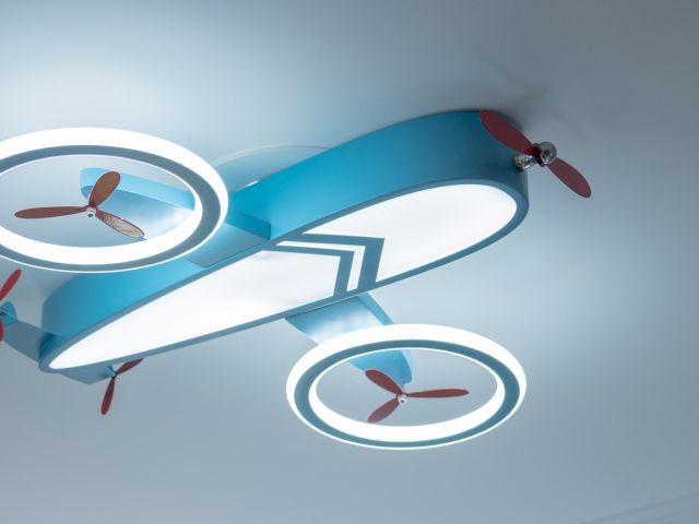 The image shows a ceiling light fixture designed to look like a toy airplane with illuminated circular propellers.