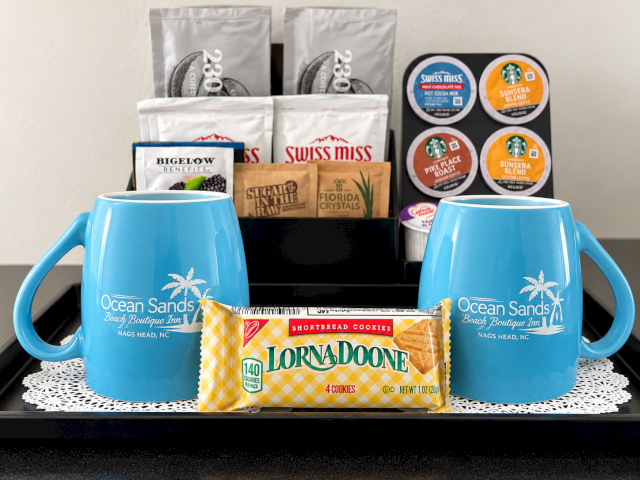 A gift set with Ocean Sands blue mugs, coffee pods, Swiss Miss mixes, and shortbread cookies.