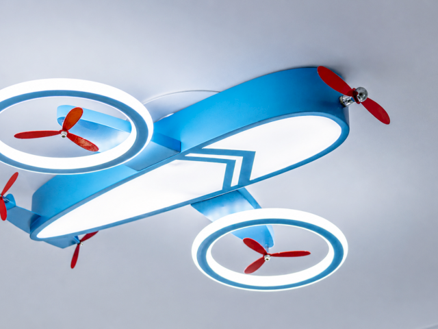 A blue airplane toy with glowing circular engines and red propellers in a bright studio scene.