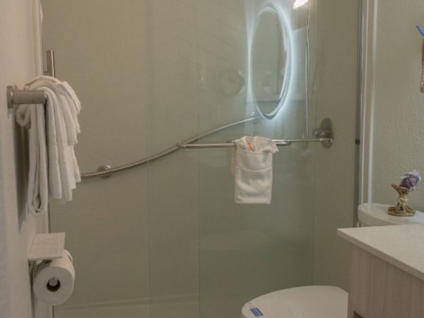 A modern bathroom with a toilet, glass shower, showerhead, and white towels.
