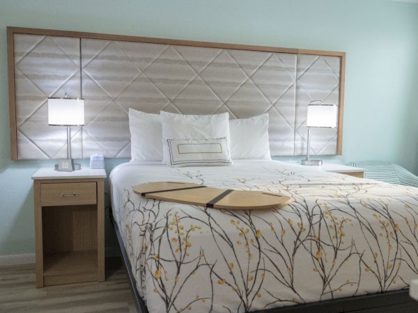 A bright bedroom featuring a neatly made bed with white pillows, decorative bedding, and two bedside lamps.