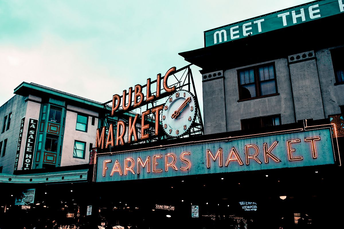 The image shows a sign for a public farmers market with a clock, likely a popular landmark in an urban area.