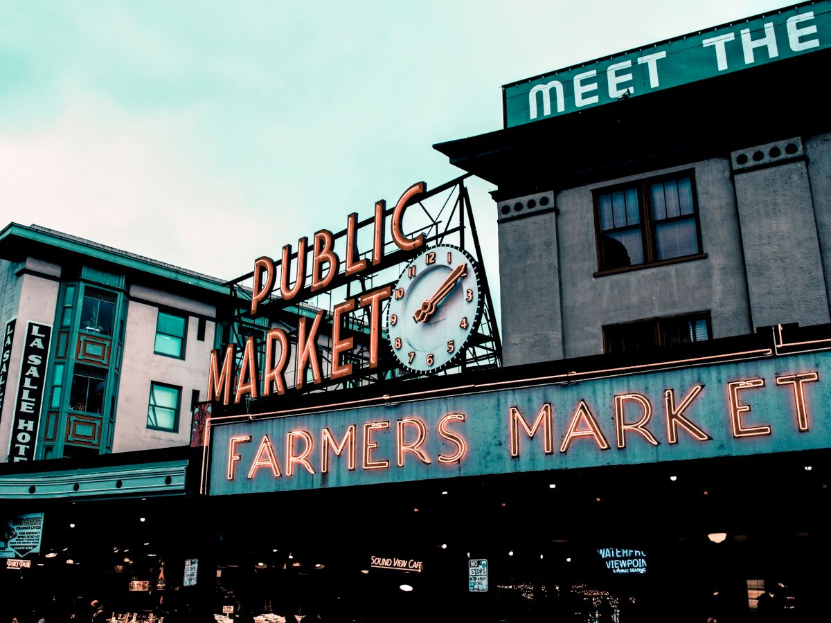 The image shows a sign for a public farmers market with a clock, likely a popular landmark in an urban area.