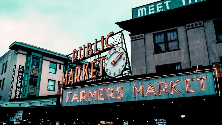The image shows a sign for a public farmers market with a clock, likely a popular landmark in an urban area.